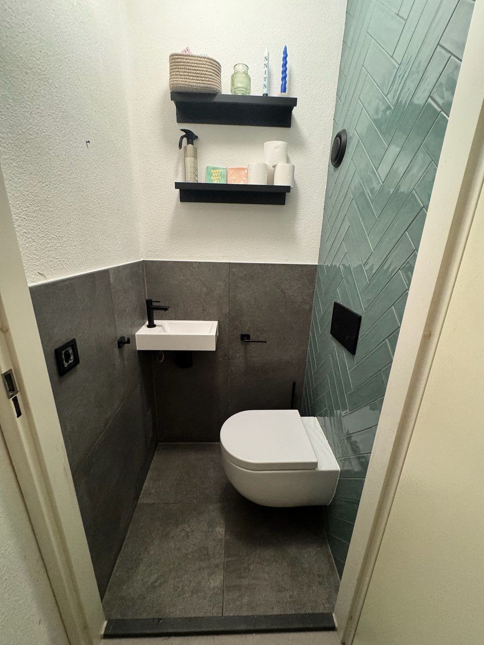 Opgeleverd toilet met groene wandtegels, hangtoilet en zwarte accenten